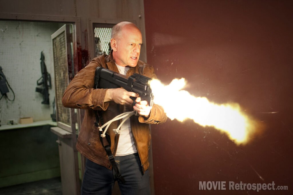Looper - Movie Still - Bruce Willis Guns Blazing